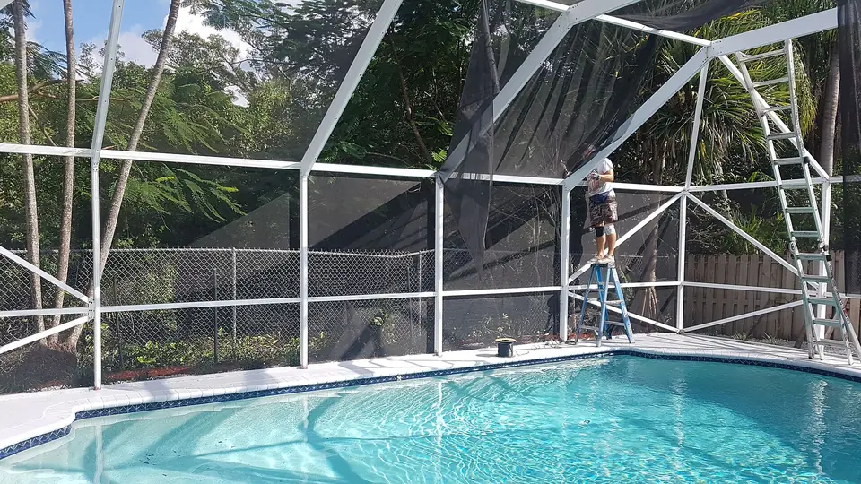 Worker on a white aluminum pool screen enclosure